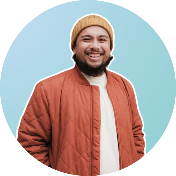 A smiling man with a beard wears a mustard beanie, white shirt, and orange quilted jacket, standing against a light blue gradient background framed in a circular border, perfect for a social media scheduler | plannthat.com A smiling man with a beard wears a mustard beanie, white shirt, and orange quilted jacket, standing against a light blue gradient background framed in a circular border, perfect for a social media scheduler | plannthat.com